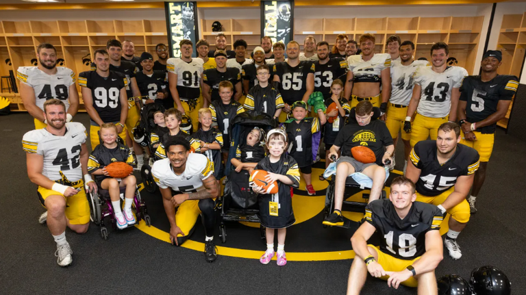 2025 Kids Captains pose with the Hawkeye football team