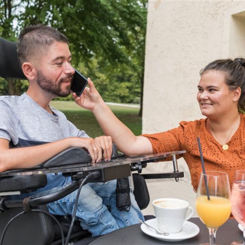 women in chair holding phone up to man in wheelchair