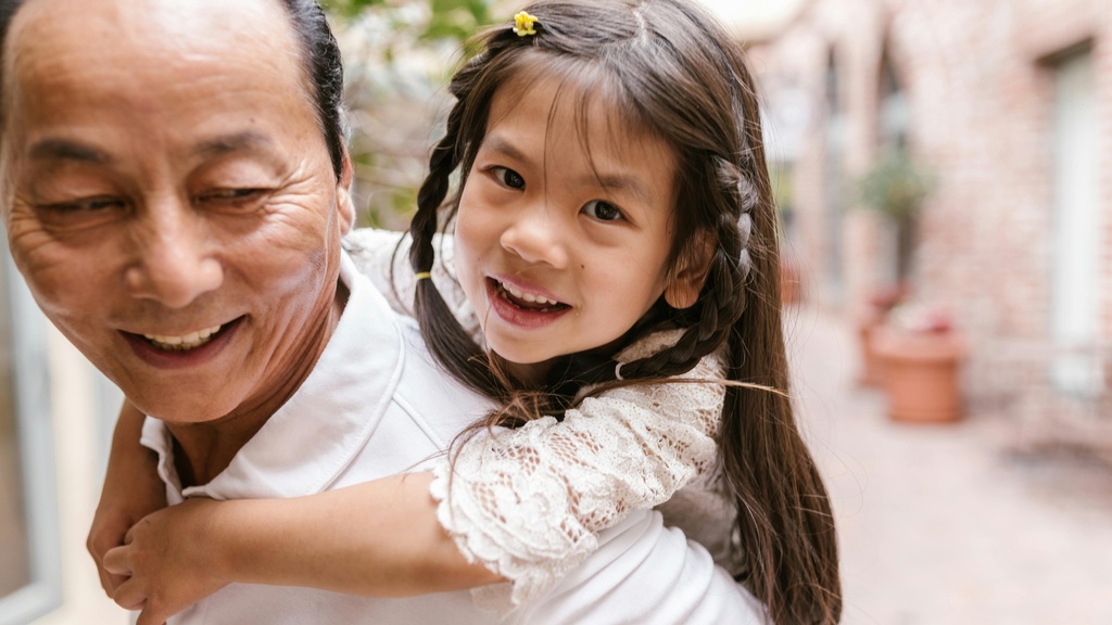 father giving daughter piggy back ride both smiling